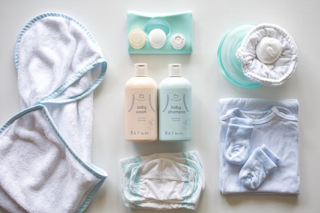 Essential baby bath time supplies laid out: baby wash, shampoo, washcloth, hooded towel, diaper, and clothes.